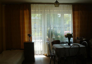 zdjęcie pokoju, przedstawiające duże okno, stolik i łóżko