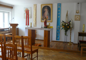 Zdjęcie przedstawia Ołtarz w Kaplicy, na którym widać zdjęcie Jana Pawła II, zdjęcie Pana Jezusa i figurkę Maryi